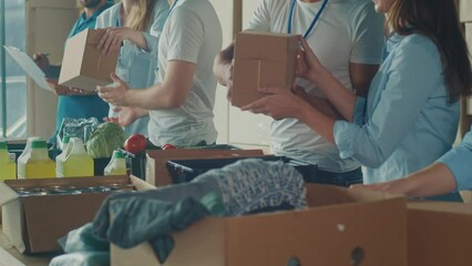 Charity, Donation, and Volunteering Concept - Group of Happy Smiling Volunteers Sorting Humanitarian Aid at Distribution or Refugee Assistance Center. Volunteer Warehouse - Powered by Adobe