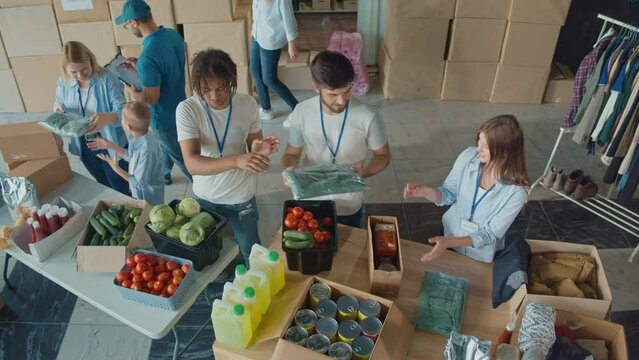 Top View. The Concept of Social Aid: Cute Young Boy Help to Volunteers to Sorting Humanitarian Aid at Distribution or Refugee Assistance Center. Charity, Donation, and Volunteering Concept.