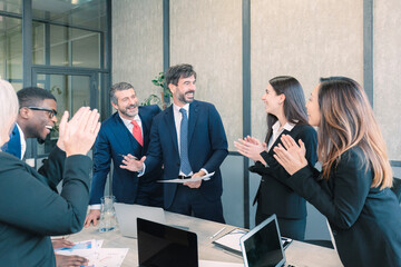 Group of multiethnic workers smiling happy and confident. Working together with a smile on your face applauding one of them in the office