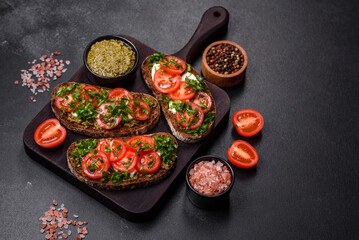 Tasty bruschetta with tomatoes, mozzarella, basil, spices and herbs