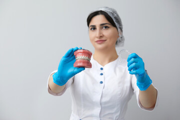 Orthodontist showing model of human jaw with wire braces and aligners explaining the difference
