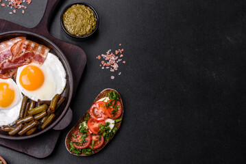 Fototapeta na wymiar Tasty breakfast consists of eggs, bacon, beans, tomatoes, with spices and herbs
