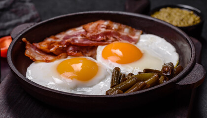 Tasty breakfast consists of eggs, bacon, beans, tomatoes, with spices and herbs