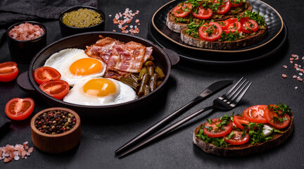 Tasty breakfast consists of eggs, bacon, beans, tomatoes, with spices and herbs
