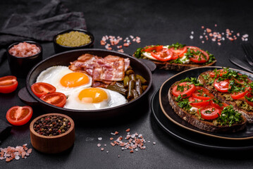 Tasty breakfast consists of eggs, bacon, beans, tomatoes, with spices and herbs