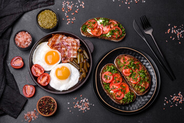 Tasty breakfast consists of eggs, bacon, beans, tomatoes, with spices and herbs