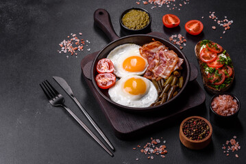 Tasty breakfast consists of eggs, bacon, beans, tomatoes, with spices and herbs