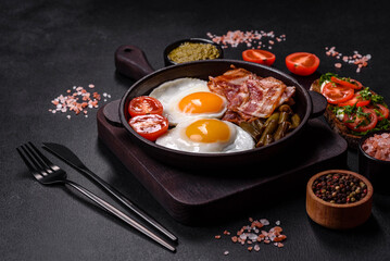 Tasty breakfast consists of eggs, bacon, beans, tomatoes, with spices and herbs