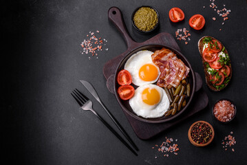 Fototapeta na wymiar Tasty breakfast consists of eggs, bacon, beans, tomatoes, with spices and herbs