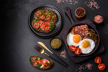 Tasty breakfast consists of eggs, bacon, beans, tomatoes, with spices and herbs