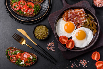 Tasty breakfast consists of eggs, bacon, beans, tomatoes, with spices and herbs