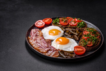 Tasty breakfast consists of eggs, bacon, beans, tomatoes, with spices and herbs