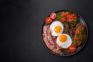 Tasty breakfast consists of eggs, bacon, beans, tomatoes, with spices and herbs