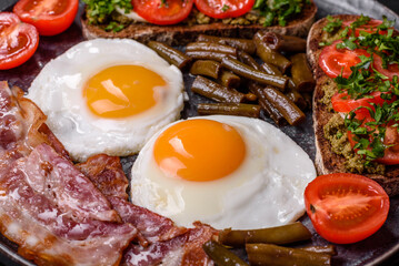 Tasty breakfast consists of eggs, bacon, beans, tomatoes, with spices and herbs