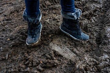 Child's feet in dirty stained boots, muddy background. Dirty in the mud warm boots. Hight quality photo