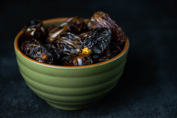 Dates fruit in bowl on dark background. Dried organic Superfood.
