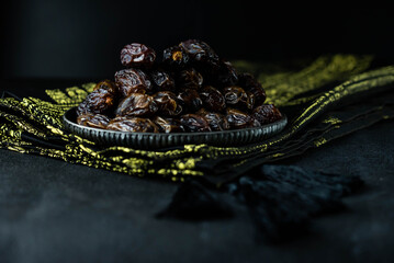 Dates fruit on oriental plate on dark background. Dried organic Superfood