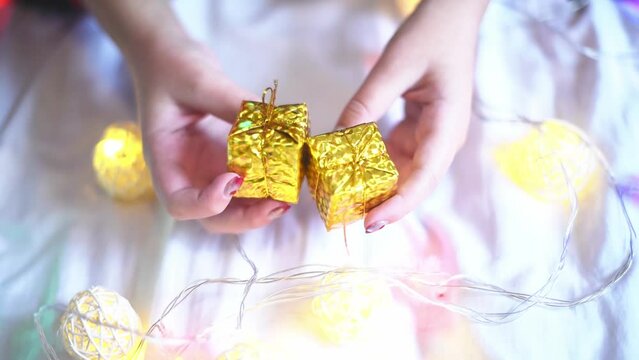 Close-up present boxes in hands ,festive mood and garlands on background. Christmas time,boxing day