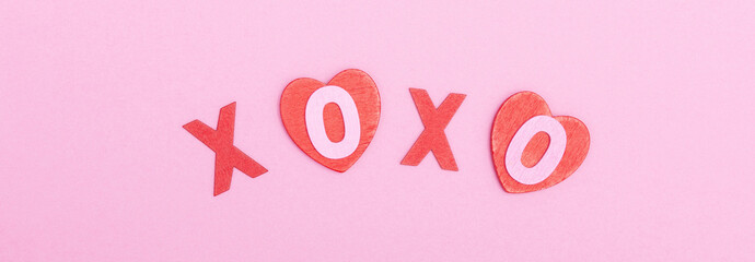 The inscription xo xo from red wooden letters on a pink background. The concept of Valentine's day, love, dating and wedding. Kiss symbol. flat lay, minimalism, web banner.