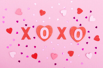 The inscription xo xo from wooden letters, glitter and hearts on a pink background. The concept of Valentine's day, love, dating and wedding. Kiss symbol. flat lay.