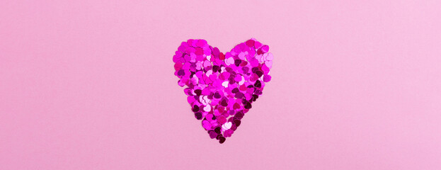 Shining heart from sparkles in the form of hearts on a pink background. The concept of Valentine's day, love, dating and wedding. Copy space, web banner.