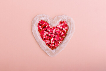 Fluffy fur heart with sparkles in the form of hearts on a red background. The concept of Valentine's day, love, dating and wedding. Copy space.