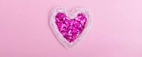 Fluffy fur heart with sparkles in the form of hearts on a pink background. The concept of Valentine's day, love, dating and wedding. Copy space, web banner.