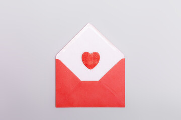 Red envelope and heart on a grey background. The concept of Valentine's day, love, dating and wedding. Symbol of love letters. Flat lay, minimalism.