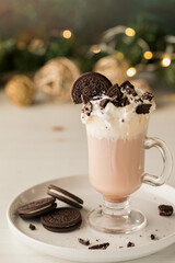 A glass cup of white hot cocoa topped with chocolate cookie crumbs.