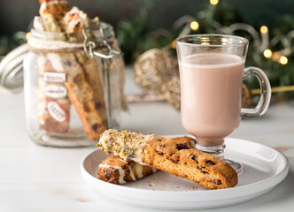 A glass cup of white hot cocoa served with biscotti for the holidays.