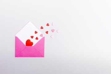Pink envelope and hearts on a gray background. The concept of Valentine's day, love, dating and wedding. Symbol of love letters. Copy space, flat lay.