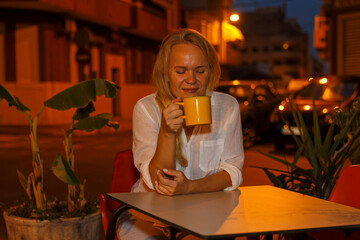 Pretty woman drinks tea or coffee in a cafe