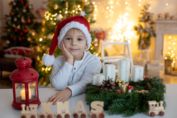 Cute preschool child, blond boy, making advent wreat at home in decorated Christmas room