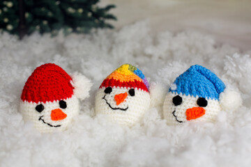 Little cute handmade snowman head with colorful hats on a sledge