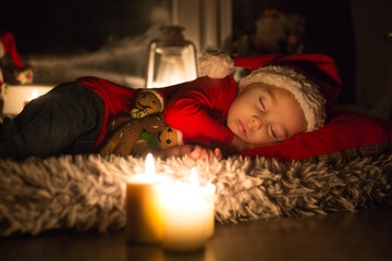 Beautiful toddler child, boy, sleeping on Christmas eve, waiting for Santa Claus to come