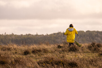Woman in yellow jacket walking on a windy hill.