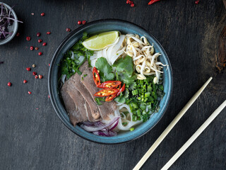 Pho Bo vietnamese Soup with beef on dark background. Top view