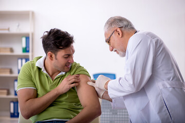 Obraz premium Young male patient visiting old male doctor in vaccination conce