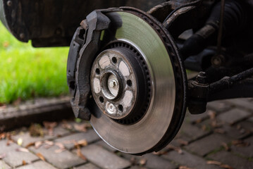 Front assembly of ventilated disc brake and wheel hub on an used car, view with removed wheel.