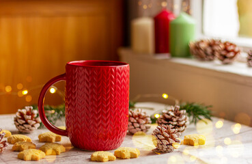 red cup with a knitted pattern on the table near the window. winter holidays, Christmas, New Year