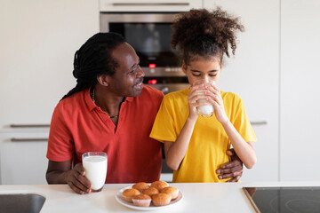 Fototapeta na wymiar Black Preteen Girl And Her Father Eating Snacks In Kitchen Together