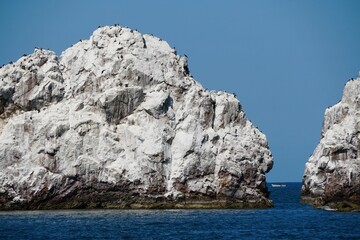 Fototapeta na wymiar The white rock island in the middle of the ocean on a sunny day near Mazatlan, Mexico