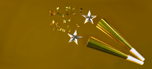 New Year celebration gold background with noisemakers, stars and confetti