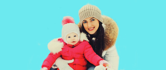 Winter portrait of happy smiling young mother and child on blue background