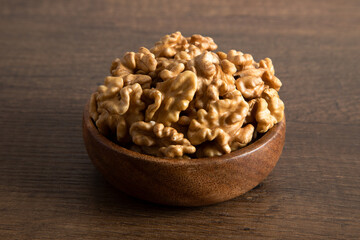 Bowl full of peeled walnuts on a wooden background