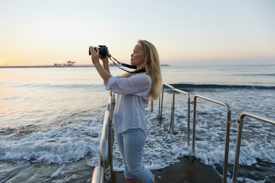 Photographer, woman and camera at beach for travel vacation or holiday in summer sun.
