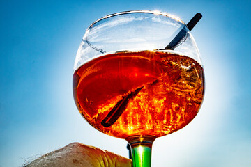 cocktail glass with straw against shiny sun