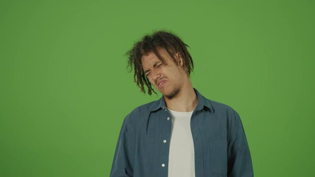 Young Multicultural Curly Freelancer Student Man in Denim Shirt Emotionally Reacting on Something Ugly, Abominable and Nasty Sticking out Tongue on Green Screen Background