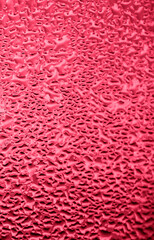 Texture of misted glass in autumn. Drops of water on window in rainy weather. Abstract background. Vertical photo. Color of the year 2023 - Viva Magenta
