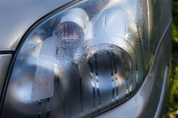 Car front light assembly covered with dew, close-up